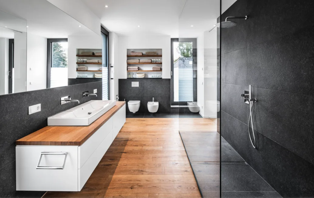Modernes Badezimmer mit dunklen Grossformatplatten, bodenebener Dusche und Holzoptikboden