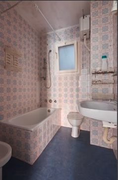 Vorher: Badezimmer mit Badewanne und alten Dekorplatten